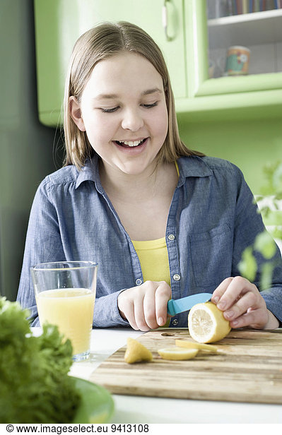 Girl in kitchen slicing lemon