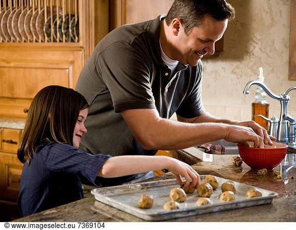 Girl in kitchen with man baking cookies