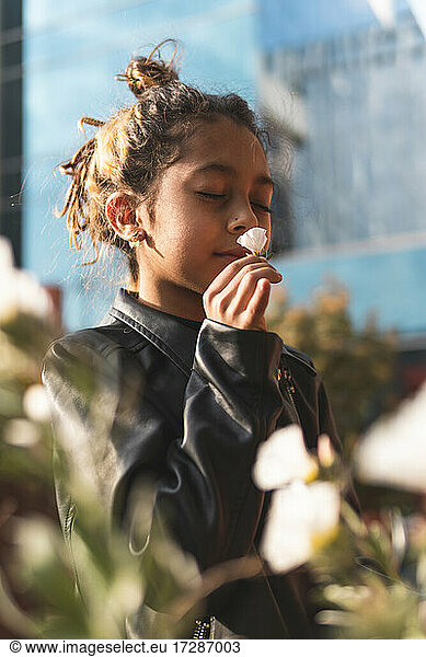 Girl in leather jacket smelling white flower