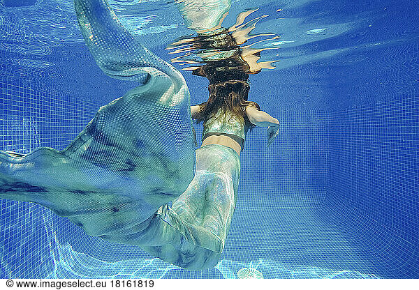 Girl in mermaid costume swimming underwater