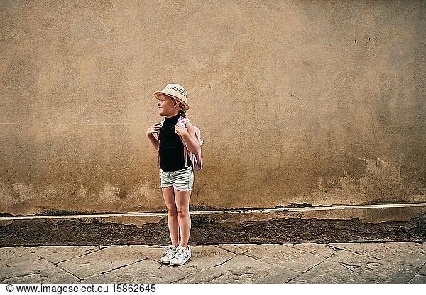 Girl in panama hat standing by old dirty wall
