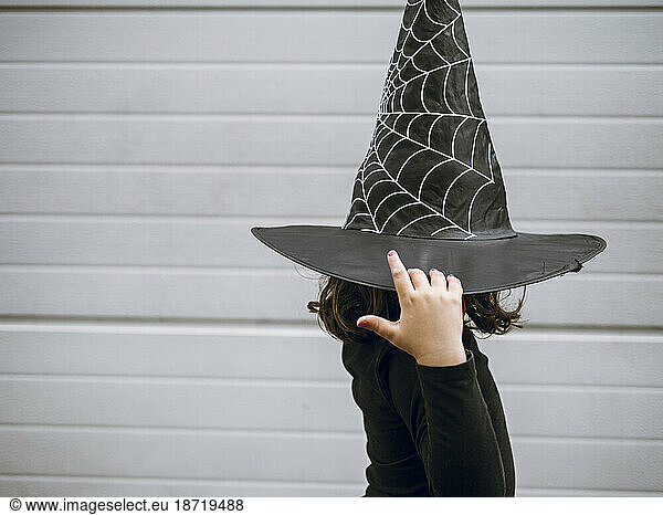 Girl in profile holding witch's cap
