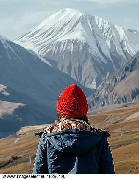 Girl in red hat portrait from back looking on mountains