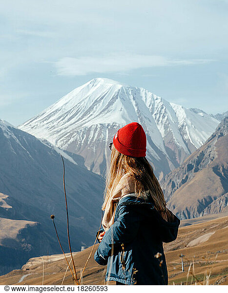 Girl in red hat portrait from back looking on mountains