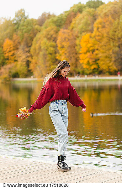 Girl in red jumper walking on the lake in park