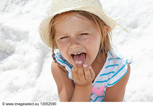 Girl in sun hat licking her fingers on beach  portrait Trapani  Sicily  Italy
