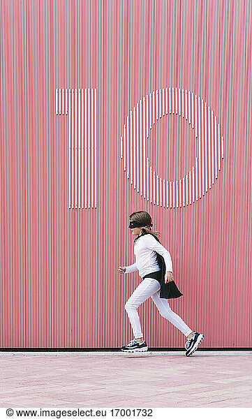 Girl in superhero costume running along a wall