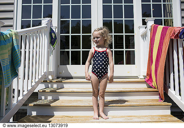 Girl in swimwear standing on steps in front of house