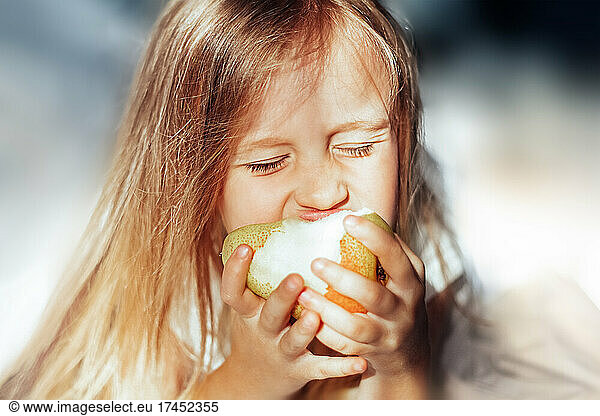Girl in the morning eating a pear in bed