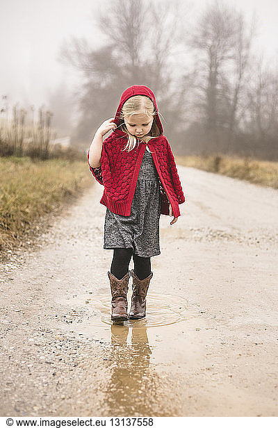 Girl in warm clothing walking on puddle