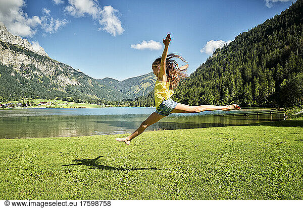 Girl jumping and doing splits in air at Haldensee lakeshore