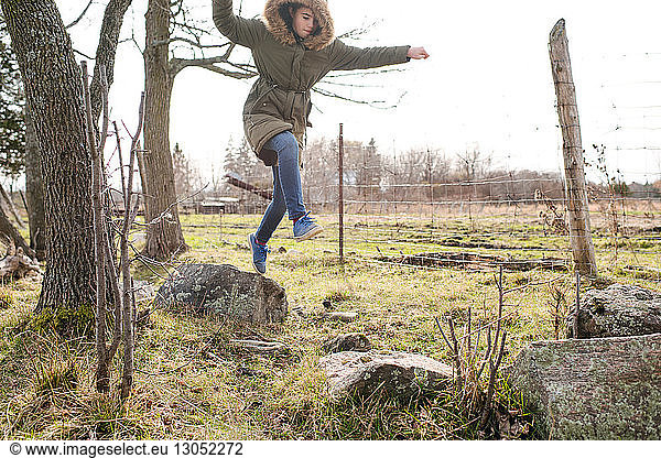 Girl jumping from rock to rock in field