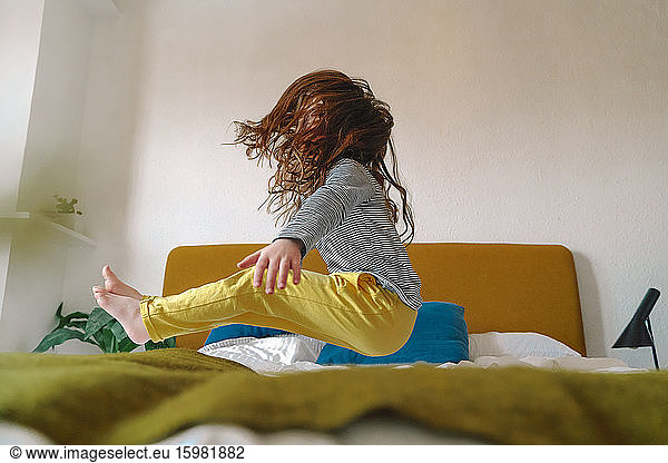 Girl jumping on bed at home