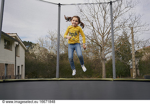 Girl jumping on trampoline in yard