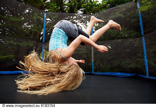 Girl jumping on trampoline outdoors