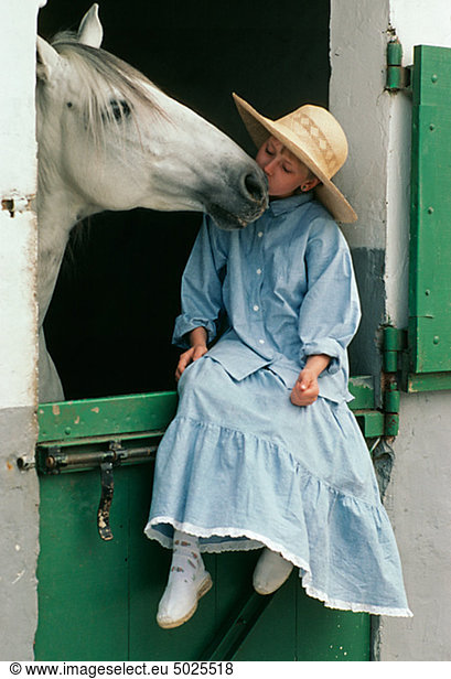 Girl kissing horse in stable