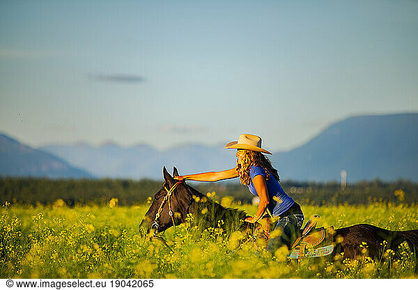 Girl laughing on horseback through a canola field in Montana