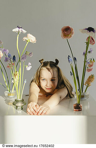Girl leaning on table amidst fresh flowers