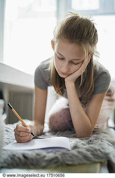 Girl learning at home  writing in exercise book