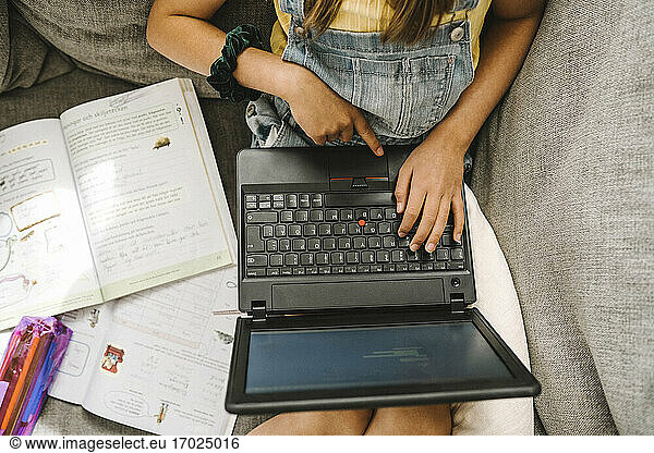 Girl learning online through laptop at home