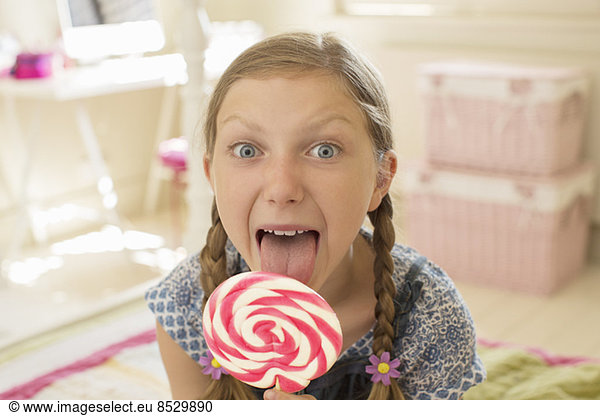 Girl licking lollipop in bedroom