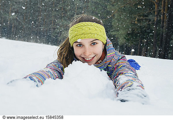girl lies in the snow and smiles