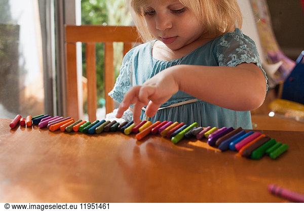 Girl lining up crayons in a row