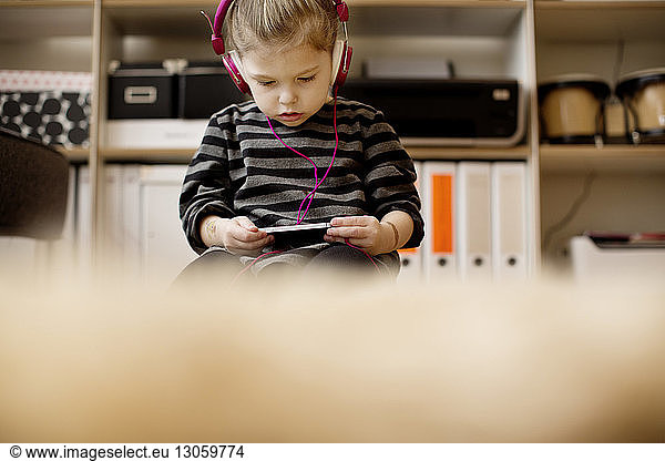 Girl listening to music while using phone at home
