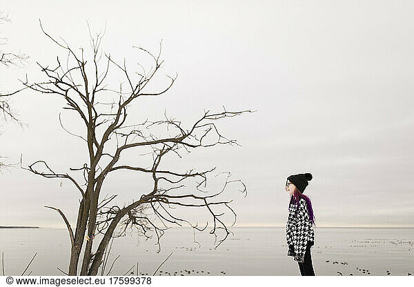 Girl looking at bare tree in winter