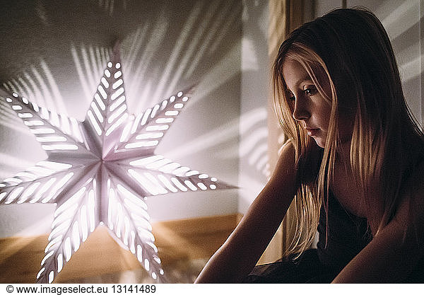 Girl looking at illuminated star shape decoration