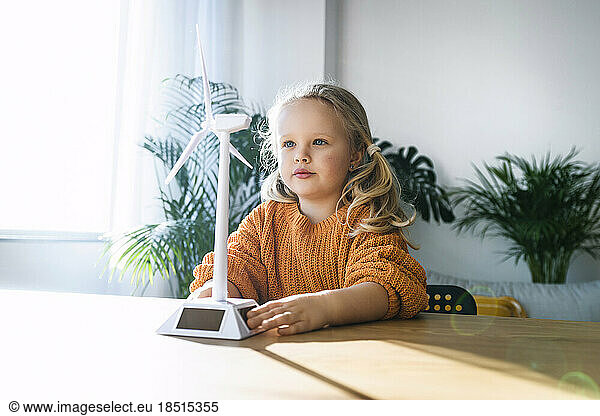 Girl looking at wind turbine model on table in green home