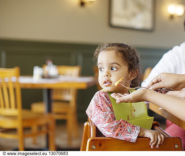 Girl looking away while parent feeding at restaurant