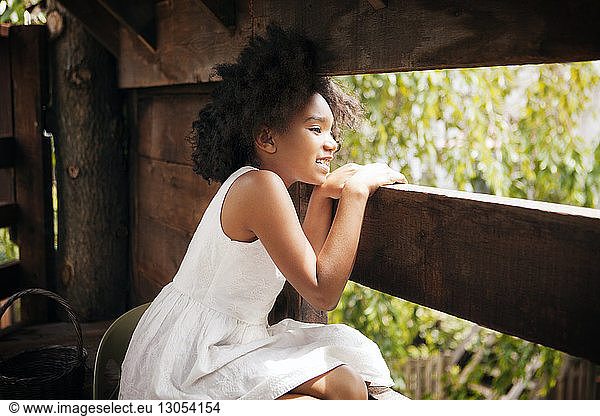 Girl looking away while sitting in tree house