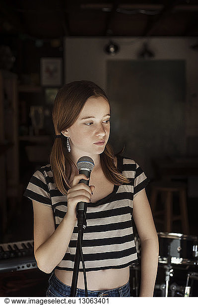 Girl looking away while standing by microphone
