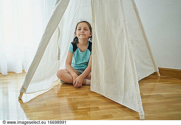 girl looking inside a white teepee tent inside their house. home concept