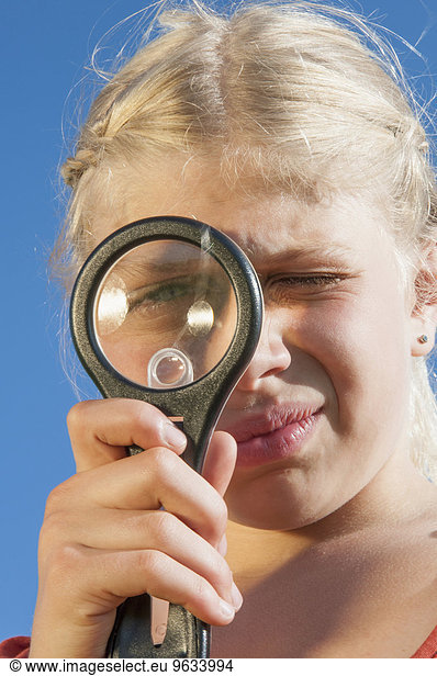 Girl (10-11) looking through magnifying glass  close-up