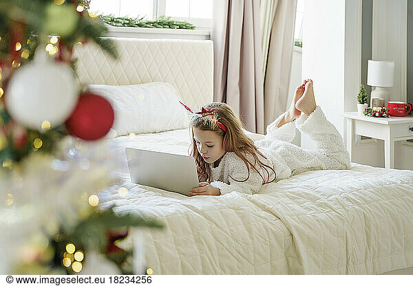 Girl lying on bed and using laptop at home