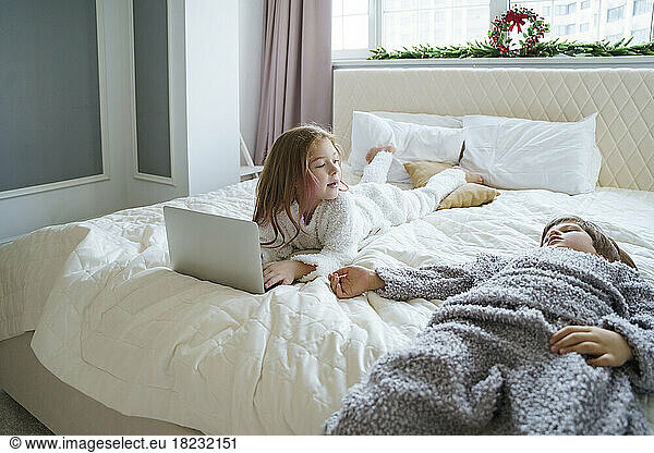Girl lying on bed with brother at home
