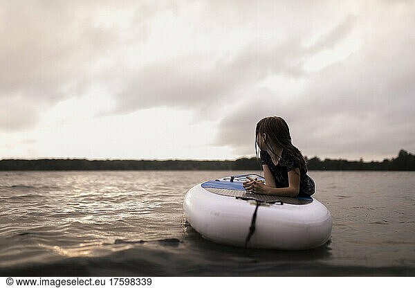 Girl lying on paddleboard at lake