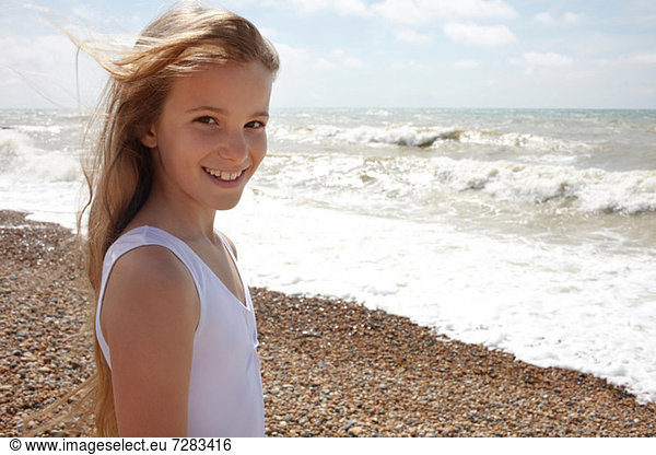 Girl on shingle beach by the sea  smiling at camera