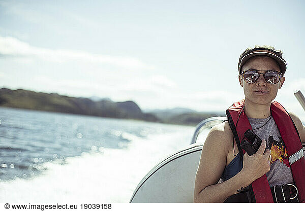 Girl on speed boat smiles in sunglasses and life vest