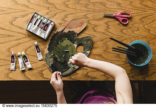 Girl painting at table from above