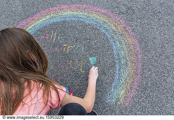 Girl painting rainbow on street with text 'Everything will fall into place'