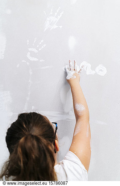 Girl painting with her finger on a wall