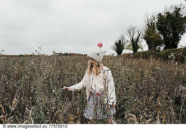 girl peacefully wandering around a wild flower field in winter