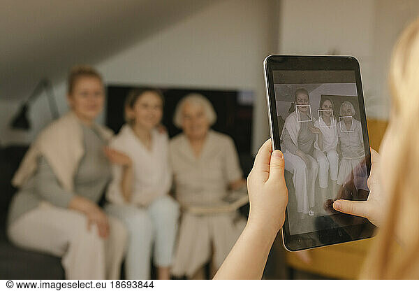 Girl photographing family through tablet PC at home