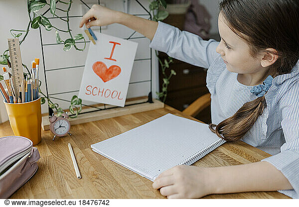 Girl pinning card on wire rack at table at home