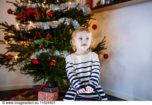 Girl playing against Christmas tree at home