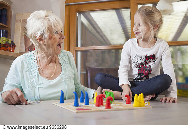 Girl playing board game with her grandmother