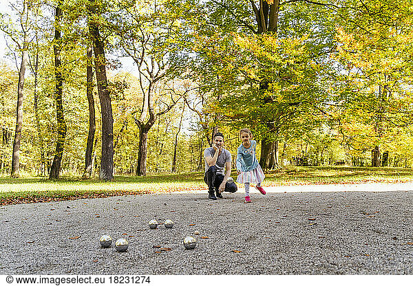Girl playing boules with father in park